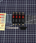 ARRMA Grom Shock Absorber Kit With 3 Spring Options, shown with red and black shocks, silver springs, and included hardware on grid.