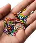 Hand holding 600 piece mixed color mini screw eye pins for jewelry making and DIY crafts, tiny eye hook pins with threads, no gold or silver.