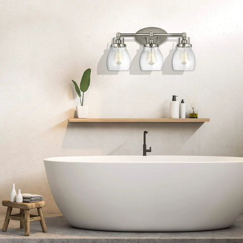 Belton Three Light Wall Bath Vanity Fixture In Brushed Nickel Finish above a modern bathtub and wooden shelf.