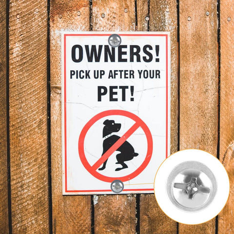 Sign on wooden fence with 'OWNERS! PICK UP AFTER YOUR PET!' and a close-up of fasteners used to secure it.