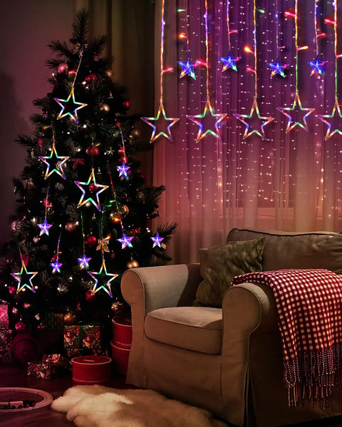 12 Star Multicolor Curtain Lights With 138 LEDs Eight Point Two Ft Connectable Window String Lights hung beside a decorated Christmas tree.