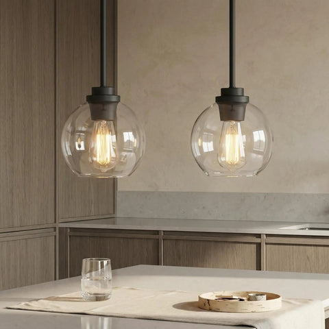 Straight Up Matte Black Globe Pendant Lights 2 Pack With Clear Glass Shades and Corrosion Resistant Metal Base above kitchen island.