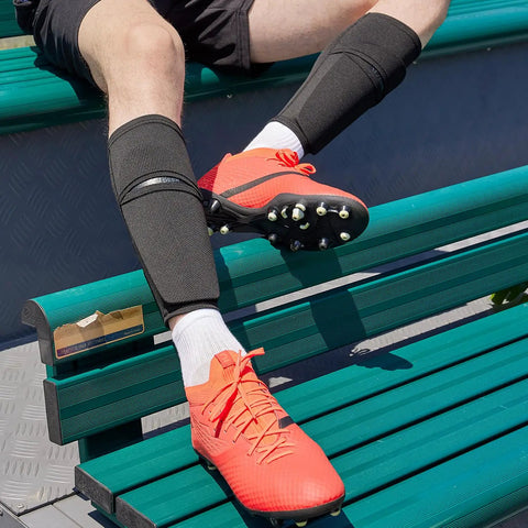 Soccer Shin Guard Sleeves With Insert Pocket And Top Lid, breathable mesh, black, size large, worn by player on bench.