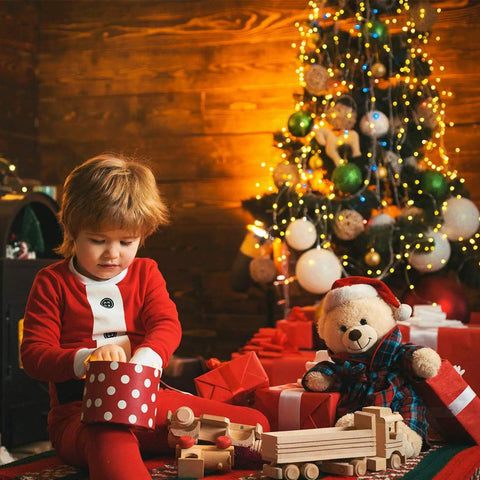Child opening gift under Christmas tree with plug in fairy lights 33ft 100 LED twinkle string lights with remote timer 8 modes.