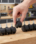 Hand holding a 1.5 inch tough nylon stem swivel caster from an 8 pack of casters for utility dolly and bin rigs.
