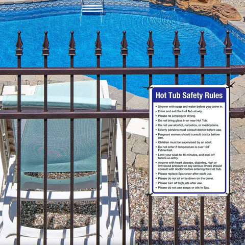 Hot Tub Safety Rules Sign For Pool Area Outdoor Durable 10x14 Inches Rust Free Aluminum Fade Resistant Made In USA Indoor Outdoor Use Weatherproof Sign That Keeps Guests In Check And Safe attached to a fence by a pool.