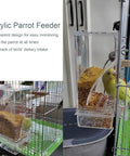 Two Pack Automatic No Mess Bird Cage Feeder Set With Clear Acrylic Food Tray And Blue Water Dispenser For Parrots shows a parrot using a transparent feeder.