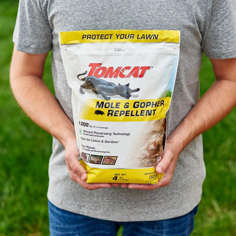 Person holding 4 lbs bag Castor Oil Based Mole And Gopher Repellent Granules for lawn, ground penetrating technology visible