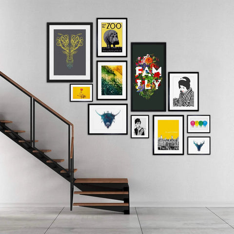 Gallery wall with various framed art prints including zoo, family, and animal designs beside a modern staircase.