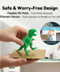 Hands holding flexible PEI plate with green dinosaur model; Kid Friendly 3D Printer For Beginners With Auto Leveling And High Speed Printing Direct Drive Extruder PLA And TPU Compatible Pre-Sliced Models On SD Card Easy Setup STEM Gift For Kids And Education
