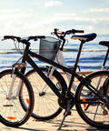 Black and white bikes with adjustable bicycle kickstand with built-in bike bell for 22, 24, 26 inch rides, parked on beach.