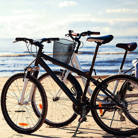 Black and white bikes with adjustable bicycle kickstand with built-in bike bell for 22, 24, 26 inch rides, parked on beach.