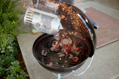 Charcoal being poured into Smokey Joe 14 Inch Portable Charcoal Grill With Tuck N Carry Lid Lock And Durable Porcelain Enamel Finish for BBQ