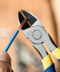 Close-up of 6 inch diagonal and flush cutting pliers with side cutters trimming copper wire, heat treated carbon steel, blue grips