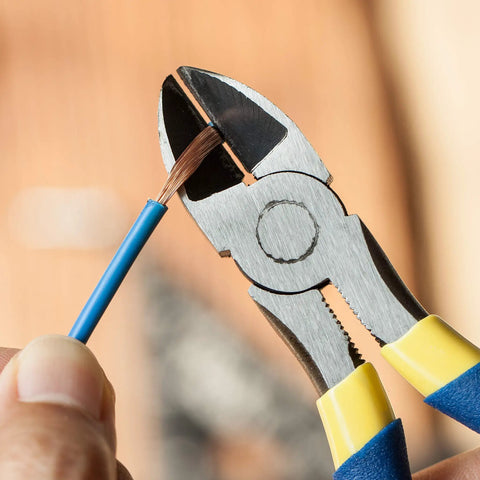 Close-up of 6 inch diagonal and flush cutting pliers with side cutters trimming copper wire, heat treated carbon steel, blue grips