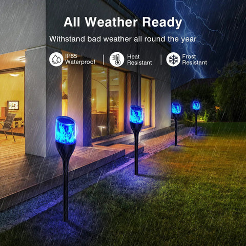 Solar Outdoor Lights 6 Pack Tiki Torches With Flickering Flame illuminating a garden pathway during rain, showcasing waterproof feature.
