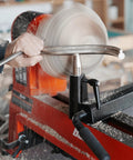 Woodturning toolrest on a red wood lathe with a spinning wooden bowl; front view