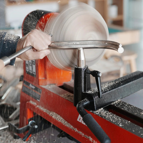 Woodturning toolrest on a red wood lathe with a spinning wooden bowl; front view