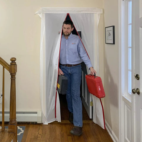 Man walking through ZipDoor ZDM Magnetic Door Kit self-closing door with red trim for dust barriers during renovation.