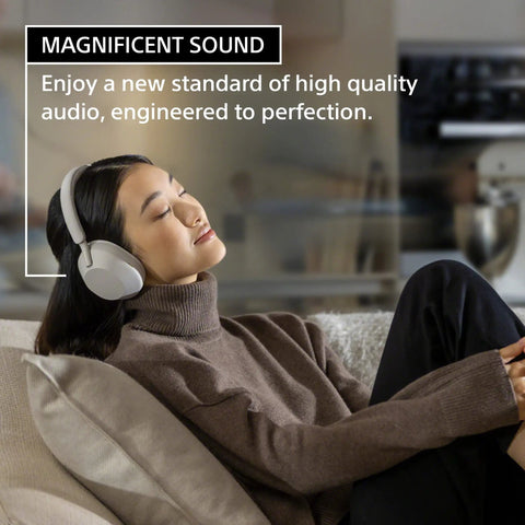 Person relaxing with WH-1000XM5 Premium Noise Canceling Headphones With Auto NC Optimizer All Day Battery Life black on sofa.