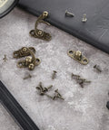 Two Piece Bronze Zinc Alloy Swing Arm Hasp Latch Set With Heavy Duty Mounting Screws For Jewelry Boxes Cabinets And Toolboxes on a work surface.