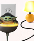 Star Wars Mandalorian Baby Yoda talking night light with clap activated switch plugged into wall outlet, lamp nearby