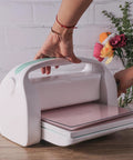 Manual Die Cutting Machine For Scrapbooking And Card Making, 9 Inch Opening, being used on a wooden table with flowers nearby.