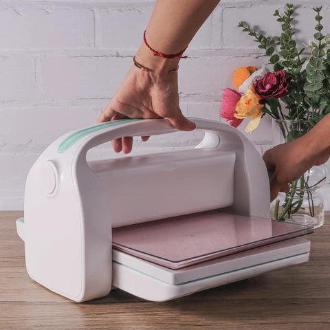 Manual Die Cutting Machine For Scrapbooking And Card Making, 9 Inch Opening, being used on a wooden table with flowers nearby.