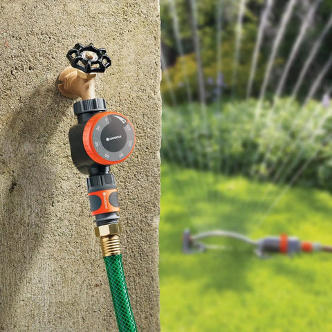 Concrete wall-mounted Easy To Use Mechanical Water Timer With Flow Control For Sprinklers And Drip Irrigation next to green lawn