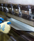 Worker wearing Heavy Duty Latex Palm Coated Safety Gloves With Kevlar Liner For Cut Resistance A3, handling metal sheet at machine.