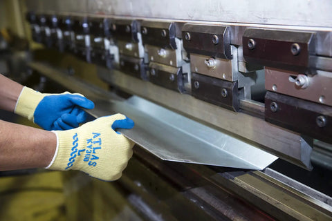 Worker wearing Heavy Duty Latex Palm Coated Safety Gloves With Kevlar Liner For Cut Resistance A3, handling metal sheet at machine.