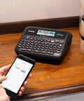 Pro Grade P-Touch PT-D610BTVP Connected Label Maker on desk with user creating label via smartphone Bluetooth connection