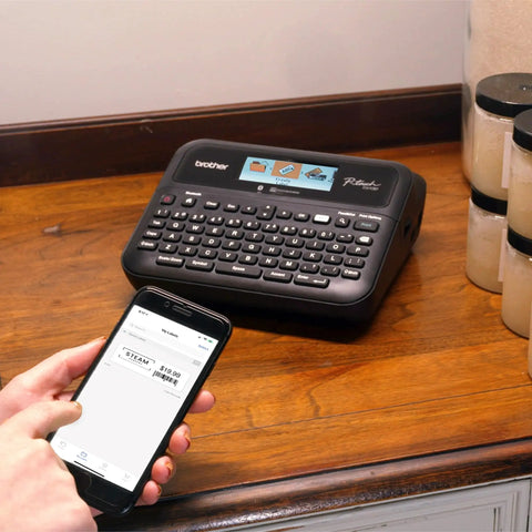 Pro Grade P-Touch PT-D610BTVP Connected Label Maker on desk with user creating label via smartphone Bluetooth connection