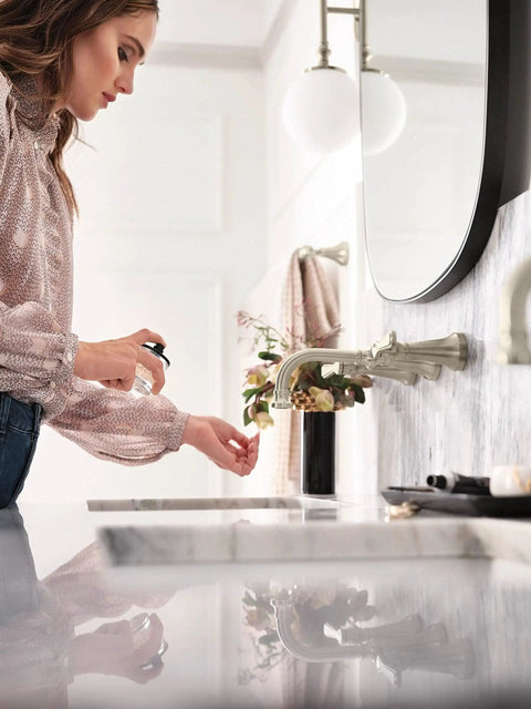 Woman using sink beside Colinet Traditional 24-Inch Towel Bar in Brushed Nickel for Bathroom, shown with attached towel.