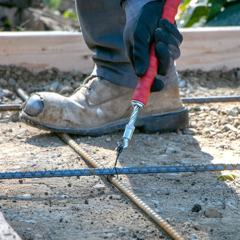 QLT Pull Tie Wire Twister for concrete and rebar tying, being used by a worker wearing gloves, 12-inch rubber grip handle.