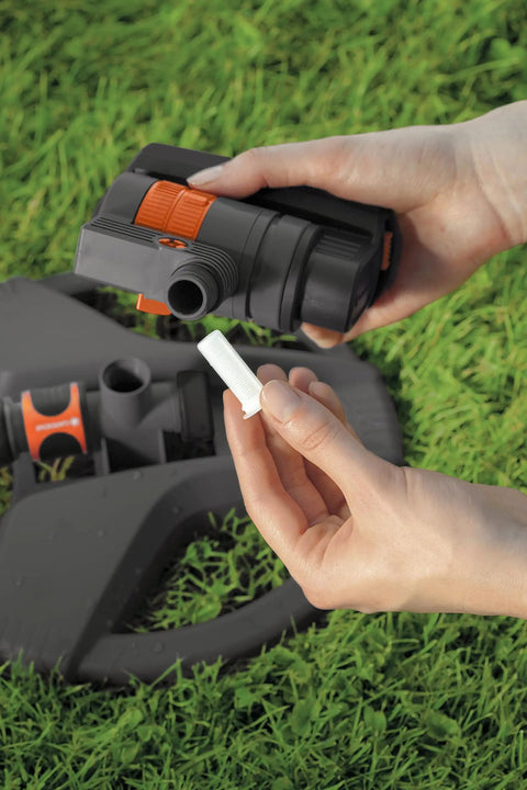 Hands showing part of ZoomMaxx Adjustable Oscillating Sprinkler On Metal Step Spike For Even Watering Of Large Lawns Up To 2300 Sq Ft