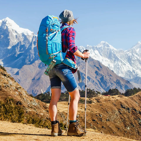 Hiker with a blue backpack overlooking mountains, utilizing Badass 3 Inch Aluminum Carabiner Clips for gear organization.