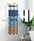 Towel rack mounted on wall with blue and brown folded towels, black metal design, dimensions shown, next to plant and bathtub.