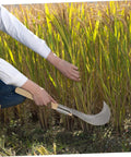 Person using Long Handle Manganese Steel Grass Sickle For Weeding And Harvesting, Hand Tool With Wooden Grip in field.