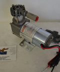 24V Onboard Air Rig For Trucks And SUVs With 120 PSI Max, 1.03 CFM, Nine Percent Duty Cycle, engine must be running, depicted resting on a table next to mounting hardware and cables.