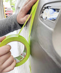 Applying Pro Grade Performance Masking Tape 233 Plus, 24 mm Wide By 55 M Long, to a car surface for precise auto body painting.