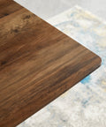 Close-up of the walnut finish wood top of the Modern Wood Top Dining Table With Sturdy Black Metal Base.