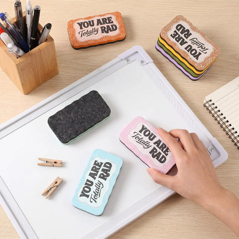 8 Pcs Magnetic Dry Erase Erasers Set In Macaron Colors for Whiteboards and Chalkboards on desk with hand holding eraser