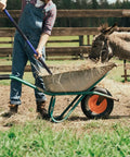 Person using Five-Tine Pitchfork For Gardening 57-Inch Heavy Duty Garden Fork With Fiberglass Handle to move hay with donkey nearby