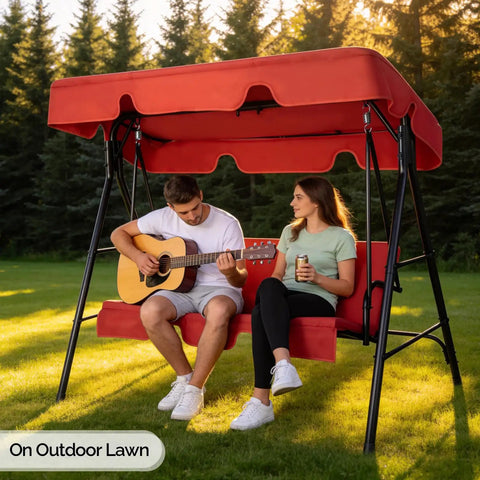 Two people sitting on Outdoor Porch Swing With Adjustable Canopy Powder Coated Steel Frame And Heavy Duty Stand For Patio Backyard Garden Or Lawn With Comfy Cushions And Weather Resistant Glider Seat In Red.