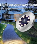 Garden path illuminated by Solar Ground Lights 12 Pack With 8 LED Waterproof Disk Pathway Lights For Yard Walkway Patio And Lawn.