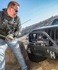 12,000 Lb Electric Winch For Trucks SUVs And Jeeps With Synthetic Rope 12V Heavy Duty Off Road Recovery Gear Built For Safe Handling And Beast Mode Spooling With Serious Pull Power mounted on a Jeep bumper
