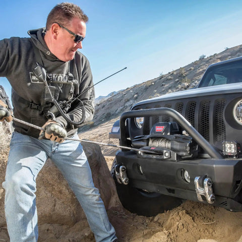 12,000 Lb Electric Winch For Trucks SUVs And Jeeps With Synthetic Rope 12V Heavy Duty Off Road Recovery Gear Built For Safe Handling And Beast Mode Spooling With Serious Pull Power mounted on a Jeep bumper