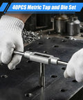 Close-up of a metal tap-and-die stock held by gloved hands over a metal workbench, part of a 40-piece metric tapping set.
