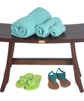 Satori Teak Shower Bench for Adults and Seniors, 24 Inch Compact Bath Seat with Brown Finish, with towels and sandals on it.